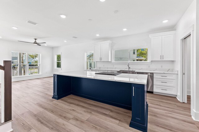 kitchen with light hardwood / wood-style floors, a spacious island, dishwasher, white cabinets, and sink