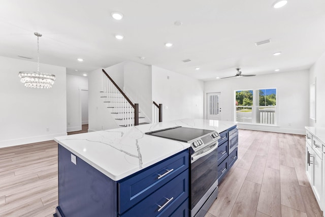 kitchen featuring a center island, light wood-type flooring, blue cabinetry, stainless steel range with electric stovetop, and ceiling fan with notable chandelier