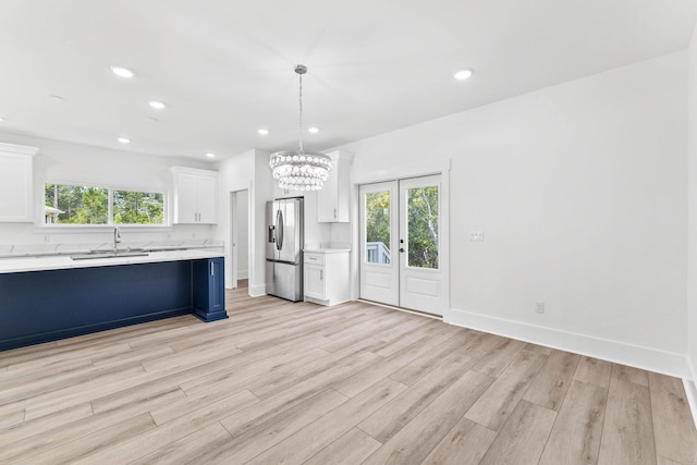 kitchen with stainless steel fridge with ice dispenser, pendant lighting, light hardwood / wood-style flooring, and white cabinets