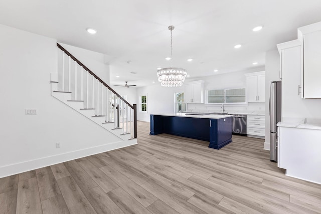 kitchen featuring a breakfast bar area, appliances with stainless steel finishes, hanging light fixtures, a kitchen island, and white cabinets