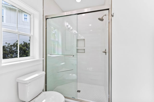 bathroom featuring a shower with shower door and toilet