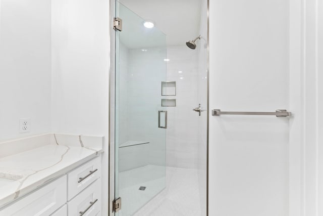 bathroom with a shower with shower door and vanity