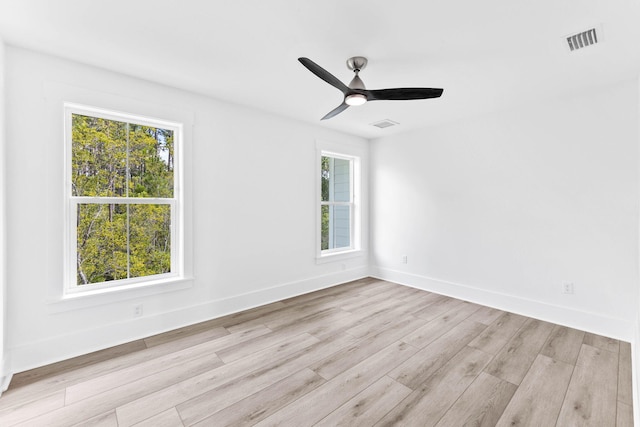 spare room with light wood-type flooring, ceiling fan, and plenty of natural light