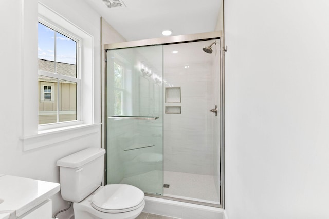 bathroom featuring toilet, vanity, and a shower with shower door