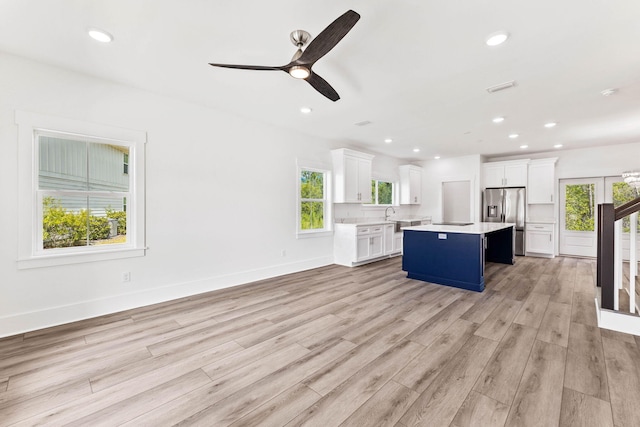 kitchen with ceiling fan, a kitchen island, white cabinetry, light wood-type flooring, and stainless steel fridge with ice dispenser