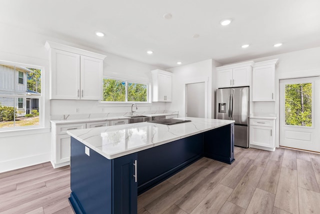 kitchen with white cabinets, stainless steel fridge, sink, and a center island