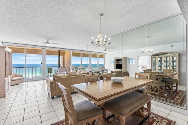 tiled dining space featuring a textured ceiling, ceiling fan with notable chandelier, and a water view