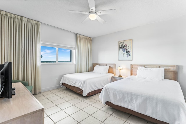 bedroom featuring ceiling fan, a textured ceiling, and light tile patterned floors