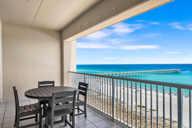 balcony featuring a view of the beach and a water view