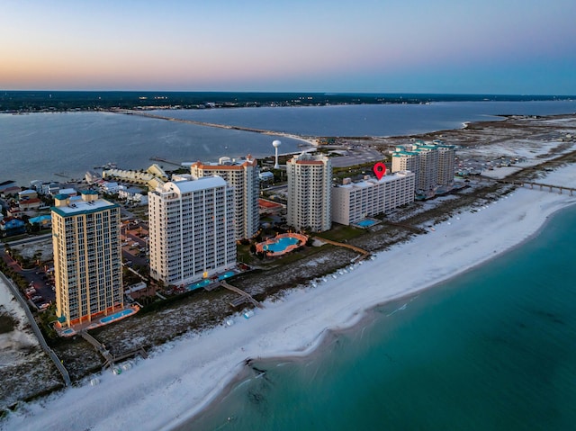 aerial view at dusk with a beach view and a water view