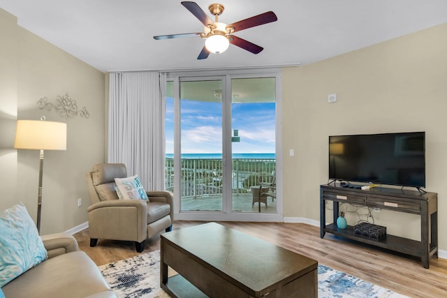 living room with a water view, ceiling fan, and light wood-type flooring