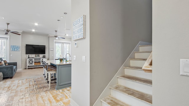 staircase featuring sink, ceiling fan, and light wood-type flooring