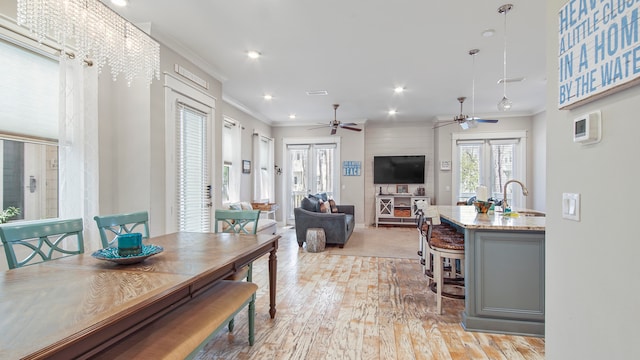 dining room with french doors, crown molding, light hardwood / wood-style flooring, sink, and ceiling fan