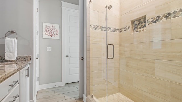 bathroom with a shower with door, tile flooring, and vanity