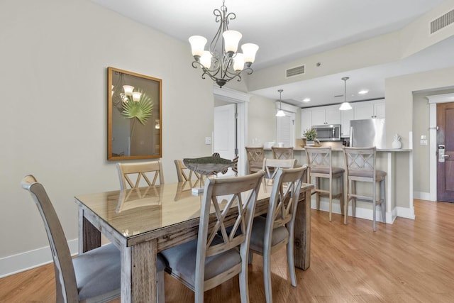 dining space featuring light hardwood / wood-style flooring and a chandelier