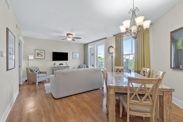 dining room featuring ceiling fan with notable chandelier and light hardwood / wood-style flooring