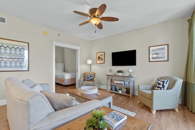 living room with light hardwood / wood-style flooring and ceiling fan