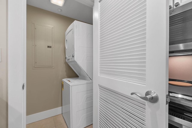 laundry room featuring stacked washer and dryer and light tile flooring