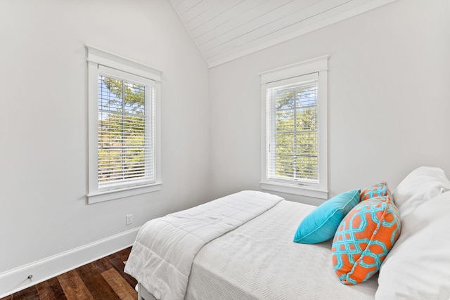 bedroom with vaulted ceiling, dark wood-type flooring, and multiple windows