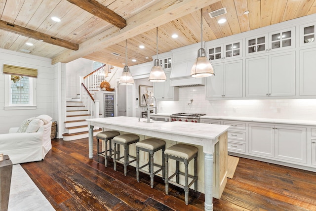 kitchen featuring a kitchen island with sink, dark wood-type flooring, hanging light fixtures, and backsplash