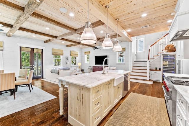 kitchen with appliances with stainless steel finishes, ceiling fan, a center island with sink, dark wood-type flooring, and pendant lighting