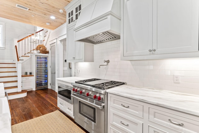 kitchen featuring backsplash, designer stove, custom range hood, white cabinets, and dark hardwood / wood-style flooring