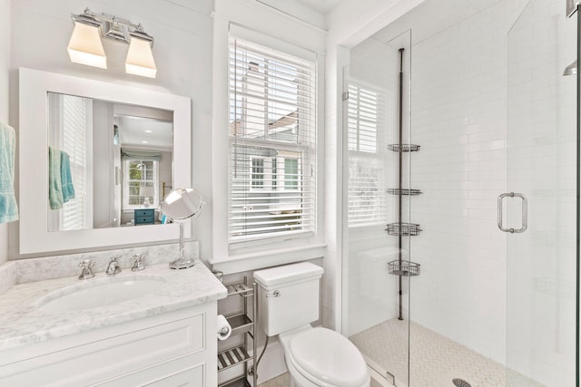 bathroom featuring oversized vanity, an enclosed shower, toilet, and a wealth of natural light