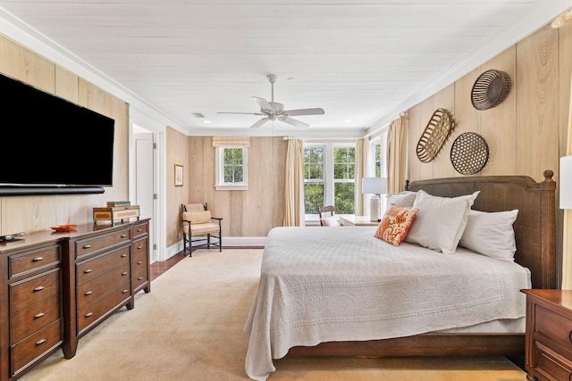 carpeted bedroom featuring wood walls, crown molding, and ceiling fan