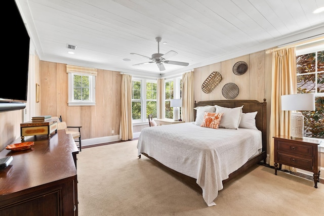 carpeted bedroom with ceiling fan, crown molding, and wooden walls