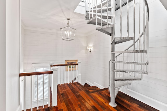 stairs with wood-type flooring, a notable chandelier, and crown molding