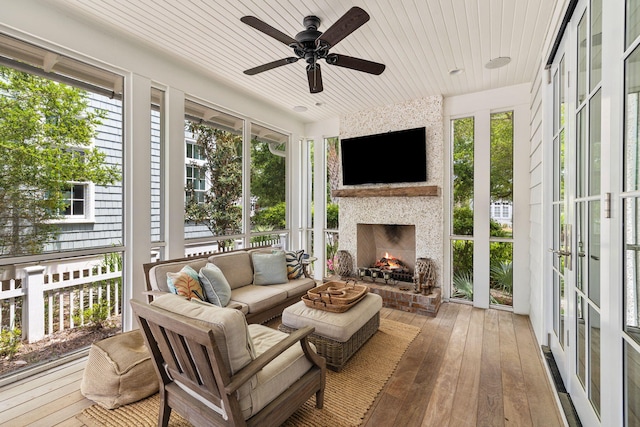 sunroom featuring wood ceiling, a fireplace, ceiling fan, and plenty of natural light