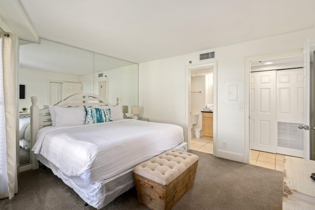 bedroom with ensuite bathroom and light carpet