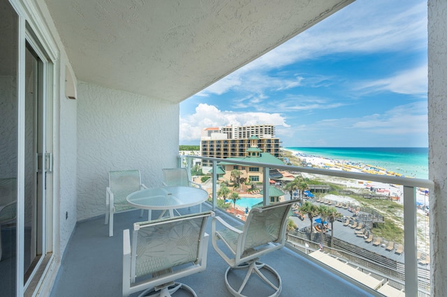 balcony with a water view and a view of the beach