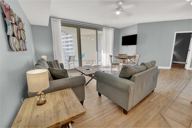 living room featuring ceiling fan, hardwood / wood-style flooring, and a wall of windows