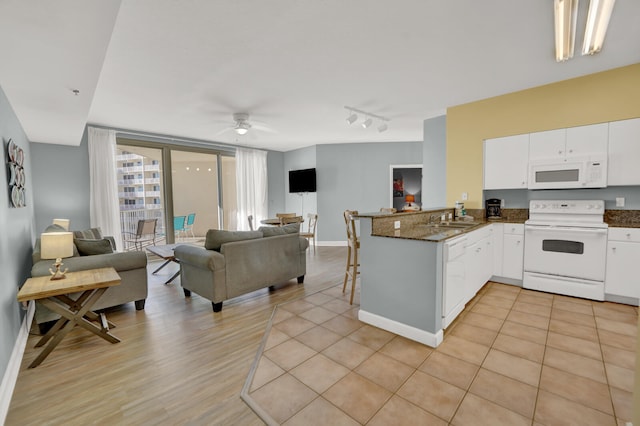 kitchen featuring white cabinets, white appliances, rail lighting, kitchen peninsula, and dark stone countertops