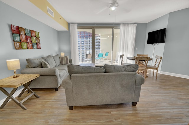 living room with floor to ceiling windows, hardwood / wood-style floors, and ceiling fan