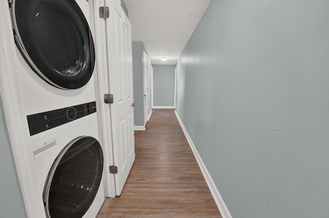 clothes washing area with stacked washer and clothes dryer and hardwood / wood-style flooring