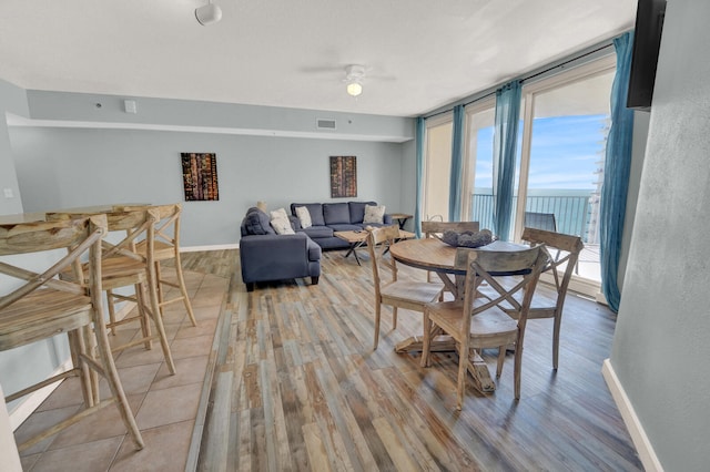 dining space with a wall of windows, hardwood / wood-style floors, and ceiling fan