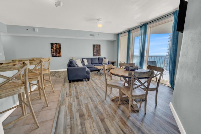 dining space with ceiling fan, expansive windows, and hardwood / wood-style floors