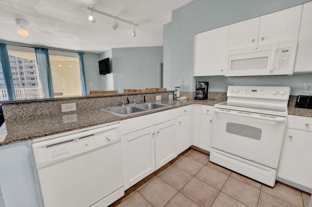 kitchen featuring white appliances, white cabinetry, kitchen peninsula, sink, and dark stone counters