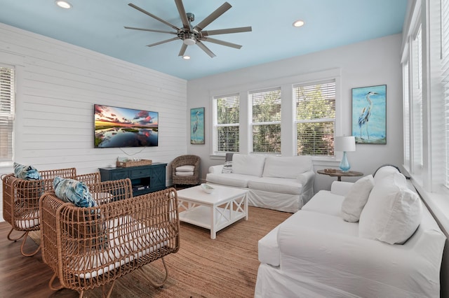 living room with wood walls, ceiling fan, and hardwood / wood-style floors