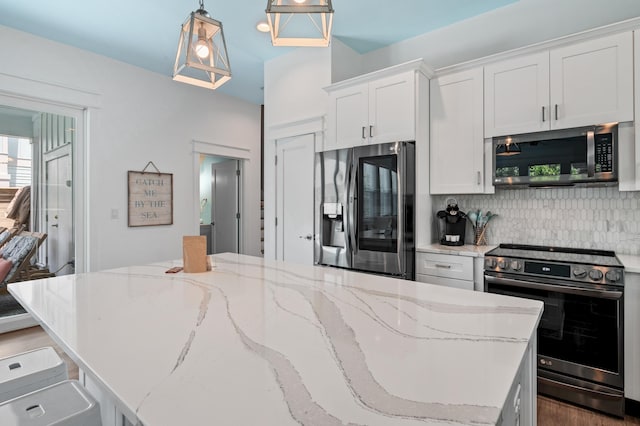 kitchen with hanging light fixtures, hardwood / wood-style flooring, stainless steel appliances, a kitchen island, and tasteful backsplash