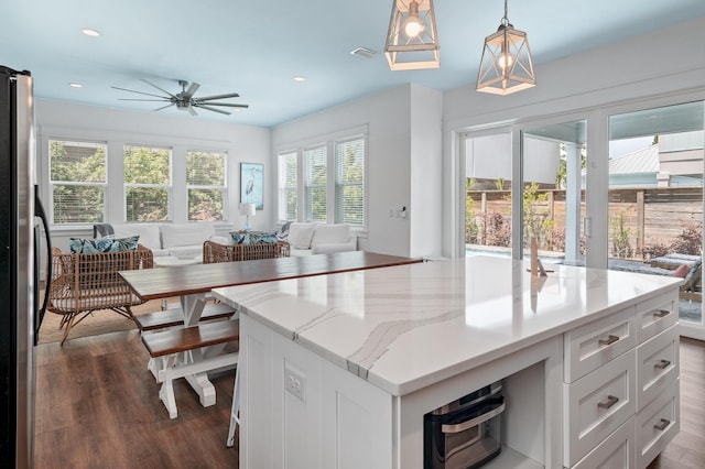 kitchen featuring decorative light fixtures, white cabinets, stainless steel refrigerator, dark hardwood / wood-style flooring, and a kitchen island