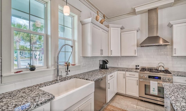 kitchen featuring white cabinetry, sink, stainless steel appliances, wall chimney range hood, and tasteful backsplash