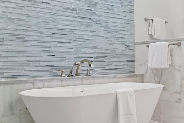 bathroom with a bathing tub, sink, and tile walls