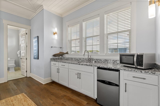 kitchen with refrigerator, sink, light stone countertops, ornamental molding, and white cabinetry