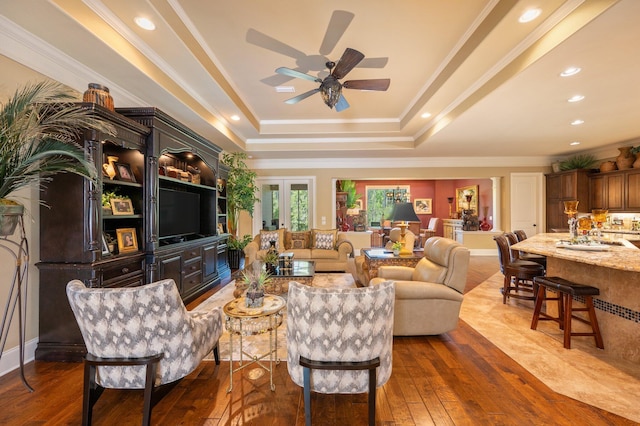 living room with ceiling fan, hardwood / wood-style flooring, sink, a raised ceiling, and ornamental molding