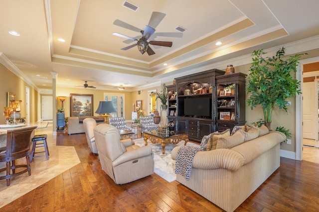 living room featuring ceiling fan, a tray ceiling, hardwood / wood-style flooring, and ornamental molding