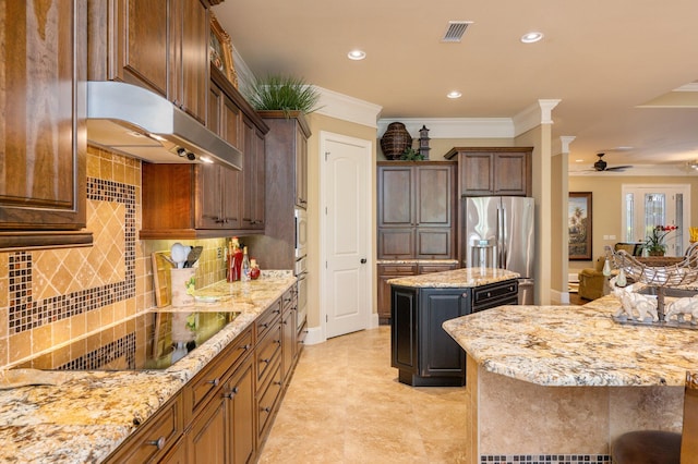 kitchen featuring a center island, backsplash, wall chimney range hood, stainless steel appliances, and ceiling fan