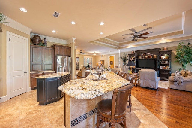 kitchen with light stone countertops, light hardwood / wood-style flooring, ceiling fan, a center island, and ornamental molding